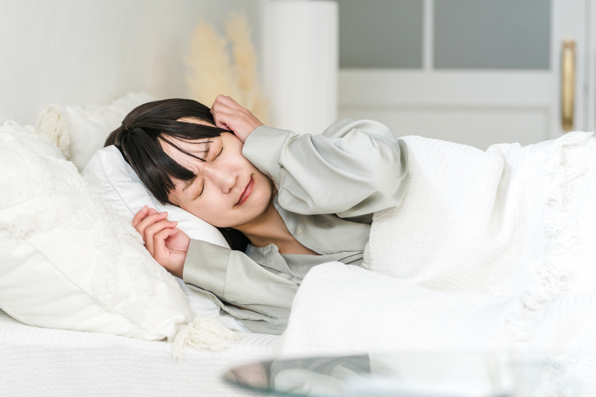 ベッドの上で苦しそうにする女性のイメージ│なぜメニエール病になるの？