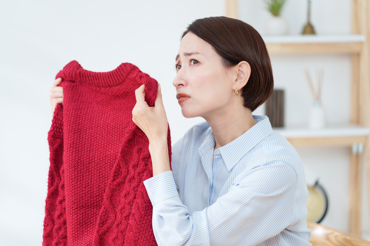 衣替えで出したセーターの臭いを嗅ぐ女性│嗅覚障害とは？原因と背景